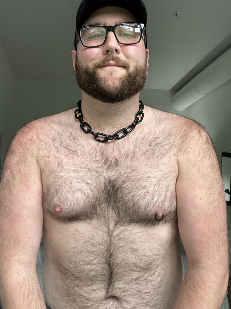 Dom (@nonviolentbear), influenceur gay tiktok, photo du modèle onlyfans portant des lunettes et une casquette